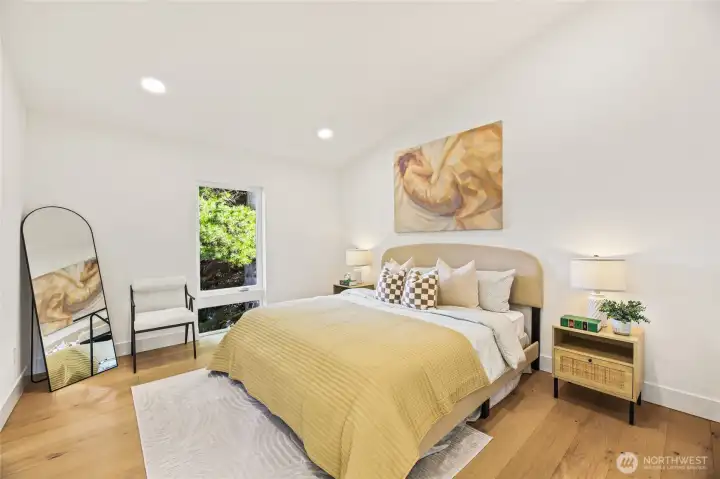 Spacious primary suite featuring floor-to-ceiling windows and wide-plank hardwoods.