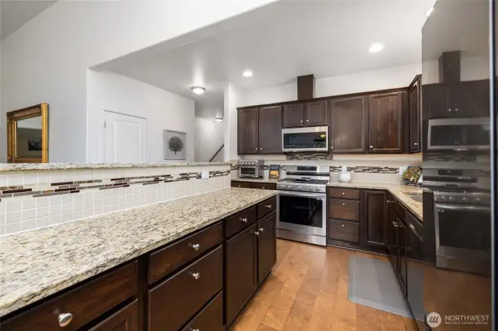Storage galore in this kitchen, with stainless steel appliances, granite countertops, and custom tile backsplash.