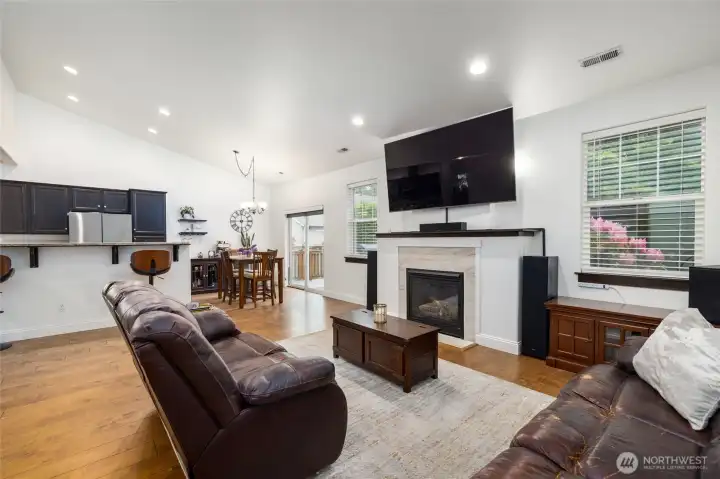 Living room is open to dining and kitchen, with gas fireplace, and engineered hardwood floors.