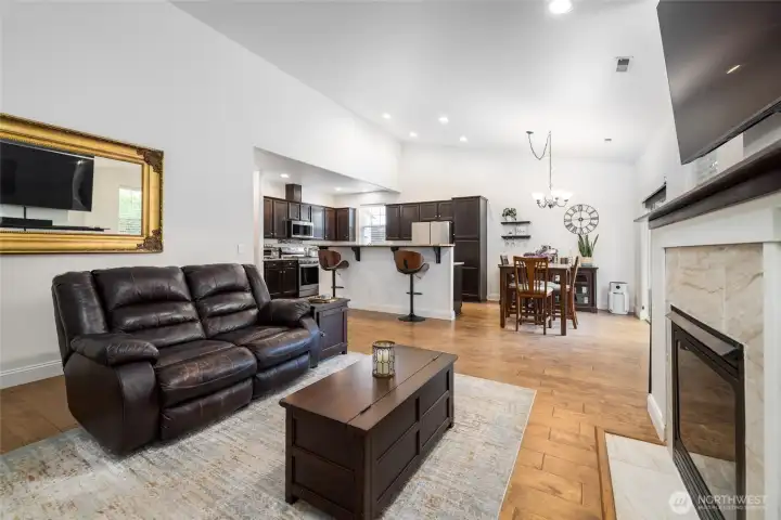 Living room is open to dining and kitchen, with gas fireplace, and engineered hardwood floors.