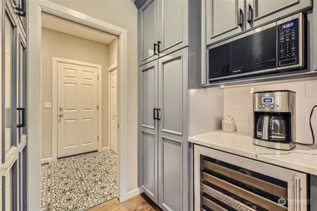 A butlers pantry with microwave, wine cooler and the gorgeous cabinetry leads into the remodeled laundry room and garage.