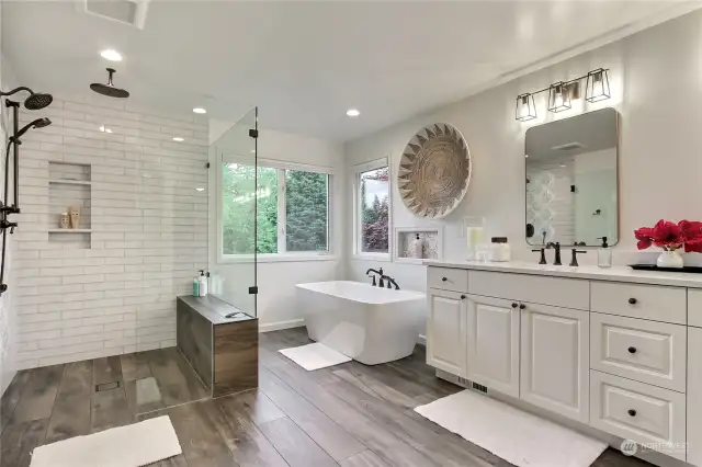 Stunning primary bath with wide plank tile flooring, modern soaking tup & updated dual vanity