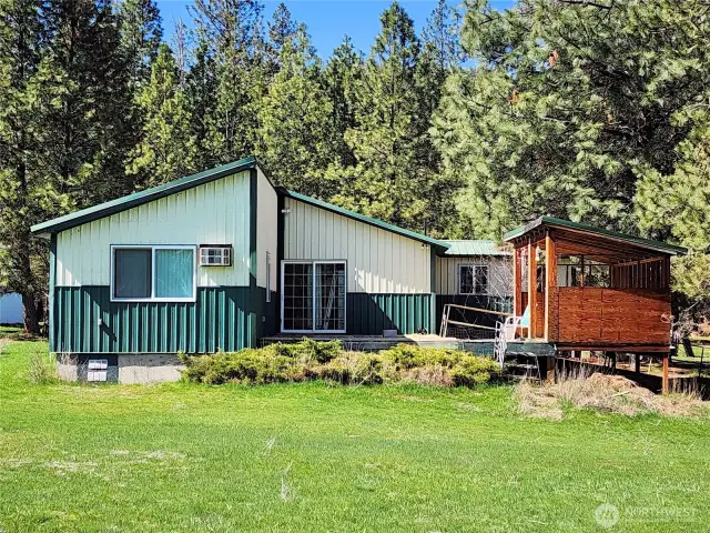 View of rear of the home. Notice the deck and the enclosed area for sitting or outdoor BBQing!