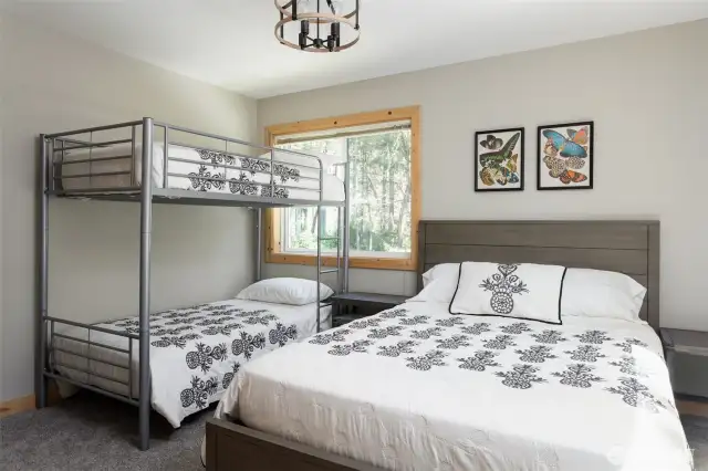 Main floor bedroom featuring a queen bed and twin bunks, and window. (Bedroom #4)