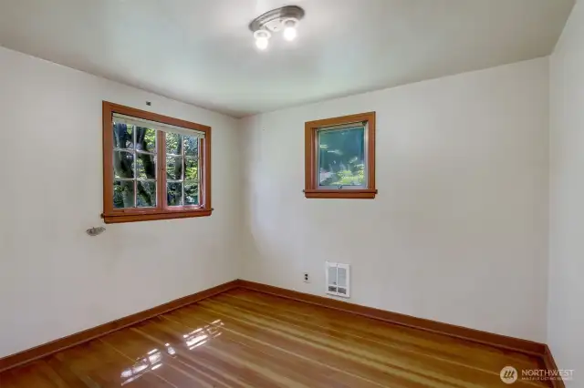 Back bedroom with pine hardwood floors, cedar lined closet and 2 large classic windows with views of the blooming backyard.
