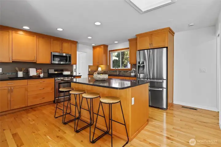 Updated timeless design kitchen with natural wood shaker cabinets, stainless steel appliances and large island with seating