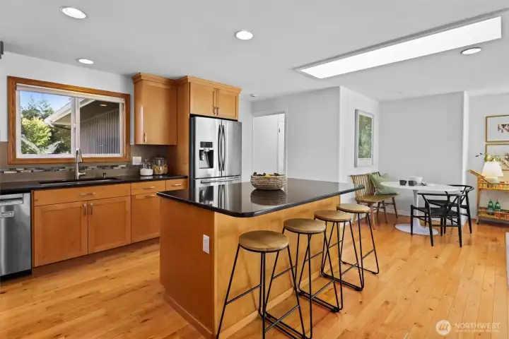 Updated timeless design kitchen with natural wood shaker cabinets, stainless steel appliances and large island with seating
