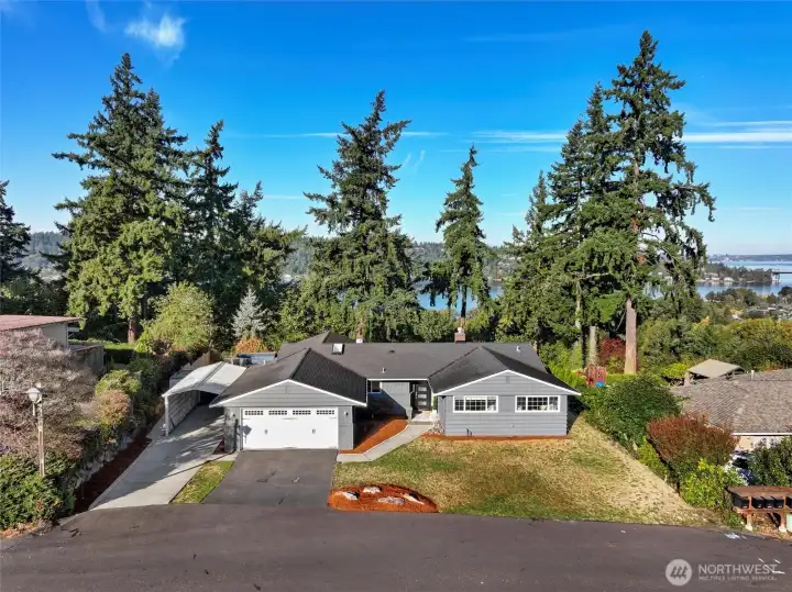 Front home with dramatic lake and city skylines behind