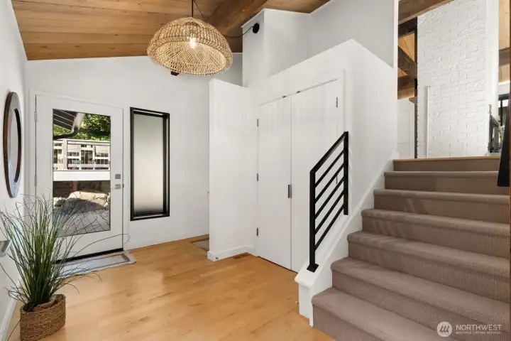 The entryway has sight lines to the backyard and a generous coat closet. The stairs to the right lead up to the living room, kitchen, and dining area. The hallway to the main floor bedrooms is to the left of this photo. The stairs to the lower levels are pictured to the left of the closet. Exterior door pictured here leads to the hot tub area!