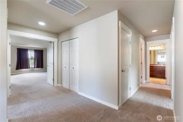At the top of the stairs looking down the hallways toward bedrooms, guest bath, laundry room and primary bedroom