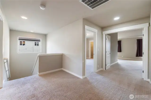 From other side of hallway looking toward stairs, bedroom and primary bedroom