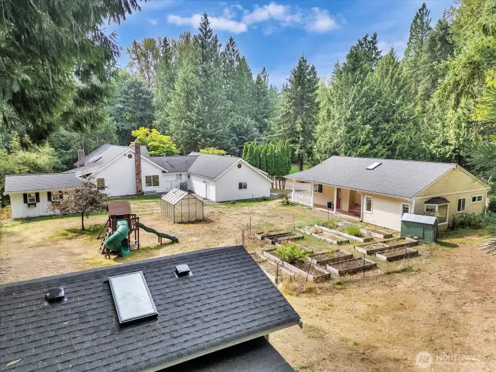 Expansive backyard with greenhouse, play area, and garden beds