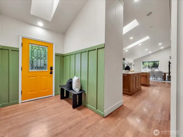 Welcoming entryway with green accents and bold orange front door