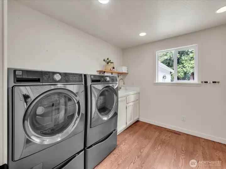 Laundry room with washer, dryer, sink, and storage cabinetry