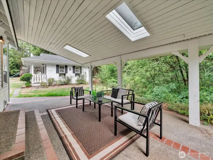 Covered outdoor patio with skylights and forest backdrop