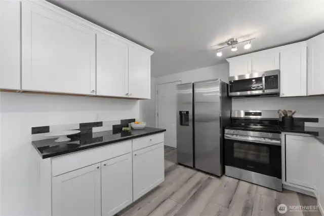 Designer kitchen with granite surfaces, custom tile backsplash, abundant cabinetry and upscale finishes