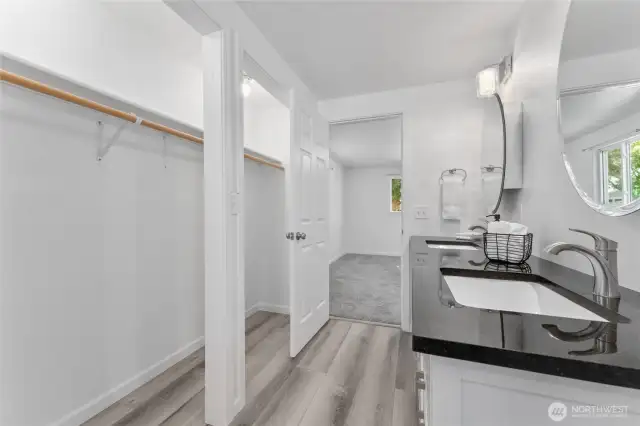 Luxury main-level retreat with oversized closet and en-suite bath complete with granite counters, dual sinks, jetted tub, and stylish lighting