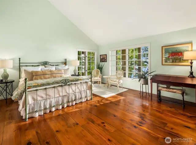 Primary bedroom with vaulted ceilings and old growth reclaimed Douglas Fir 10 inch wide plank flooring.