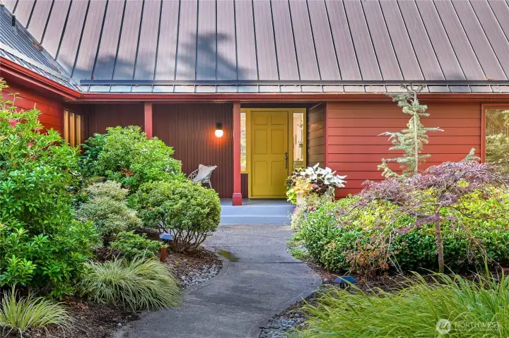 Welcome to the inviting front porch and seating area.  This is east facing, perfect for coffee in the morning!  Enjoy peaceful quiet in the vast gardens of flowering plants.  That's a newer metal roof (2023).
