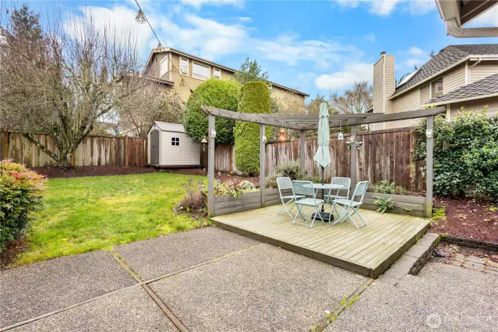 A partial view of the backyard, outbuilding for yard equipment and grassy lawn.