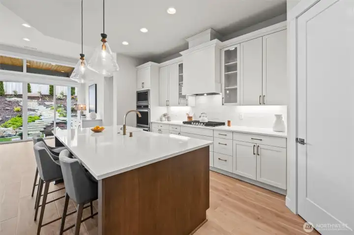Upgraded designer kitchen featuring custom cabinetry, specialty lighting, quartz countertops, stainless steel appliances, gas cooking, and dual ovens, complemented by a spacious walk-in pantry and open-concept layout in this McCormick Trails newer construction home.