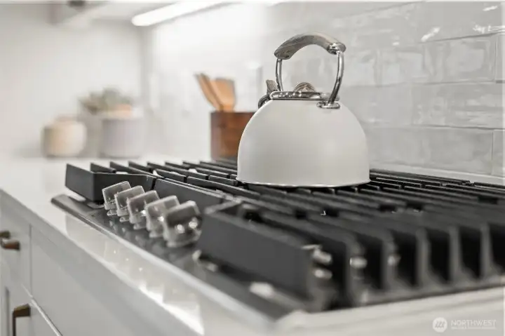 Close-up of the gas cooktop within the upgraded designer kitchen, offering precision cooking alongside quartz countertops, custom cabinetry, and elevated newer construction finishes in McCormick Trails, Port Orchard.