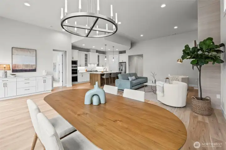 Wide view of the dining room looking toward the upgraded kitchen and wet bar, highlighting the seamless entertaining flow and open-concept design within this newer construction home in McCormick Trails, Port Orchard.