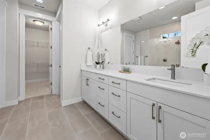 Primary ensuite bathroom featuring quartz countertops, dual sinks, and upgraded finishes, with a spacious walk-in closet just beyond and a private toilet room tucked around the corner — designed for comfortable single-level living in this newer construction McCormick Trails home.