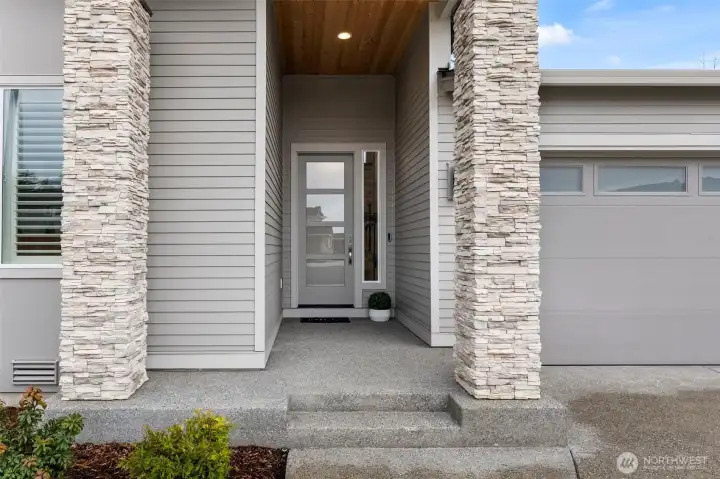 Inviting front entrance framed by ledger stone columns and featuring keyless entry, blending modern convenience with the architectural curb appeal of this upgraded newer construction home in McCormick Trails, Port Orchard.
