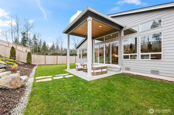 Covered patio view showcasing the dramatic wall of windows that connects indoor and outdoor living, complemented by an efficient heat pump system providing comfortable heating and air conditioning year-round in this upgraded McCormick Trails home.