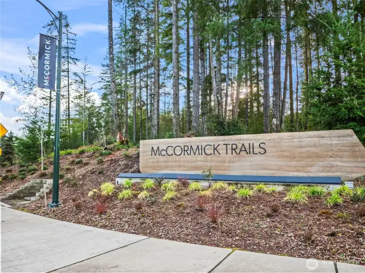 McCormick Trails community entrance featuring access to 8 miles of scenic trails, McCormick Golf Course, nearby waterfront activities, and convenient ferry connections toward Seattle, with a future village planned for boutique shops and dining.