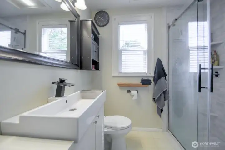 Updated bathroom featuring modern fixtures, a sleek vanity, and a spacious  walk-in shower for a clean and contemporary feel.