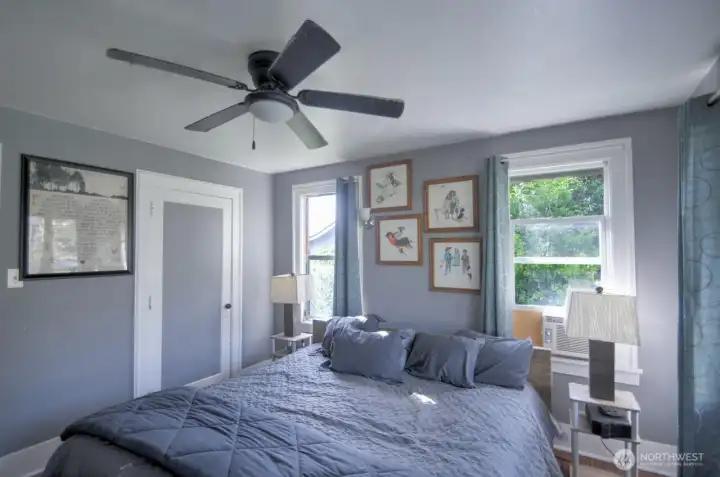 Inviting main floor primary bedroom featuring abundant natural light, hardwood floors, and a peaceful setting designed for comfort and relaxation.