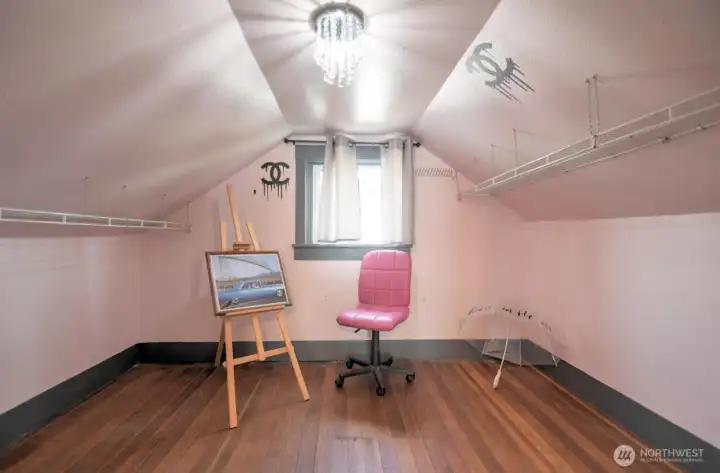 Cozy upstairs bedroom with charming angled ceilings, hardwood floors, and flexible space perfect for a guest room, office, or creative studio.