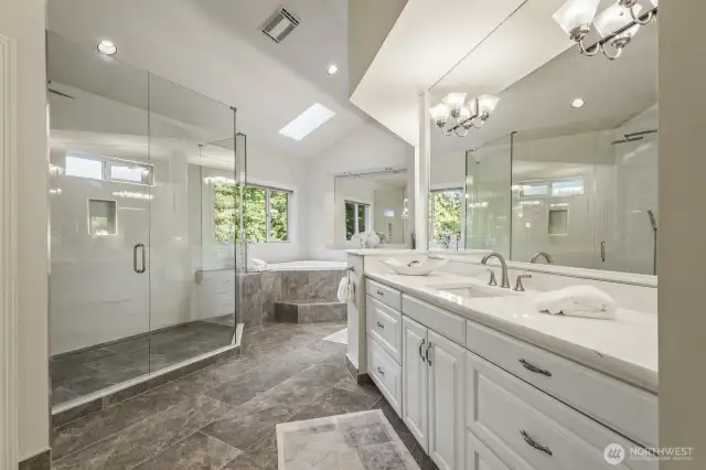 Uplifting and updated 5 piece bathroom with designer tiled floor and shower, 2-person jetted tub, make-up vanity, crisp white cabinetry with separate quartz vanities.