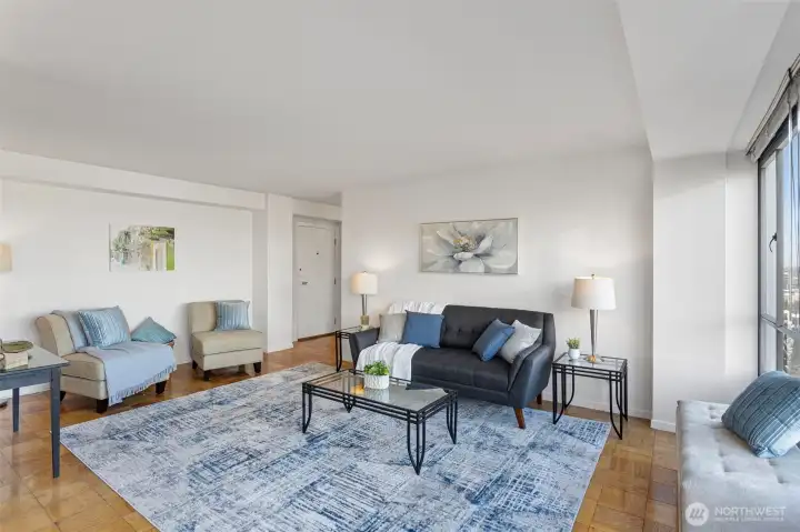 A calm, open living room with an easy line to the bedroom and bath—simple flow, generous wall space, and warm original wood floors.