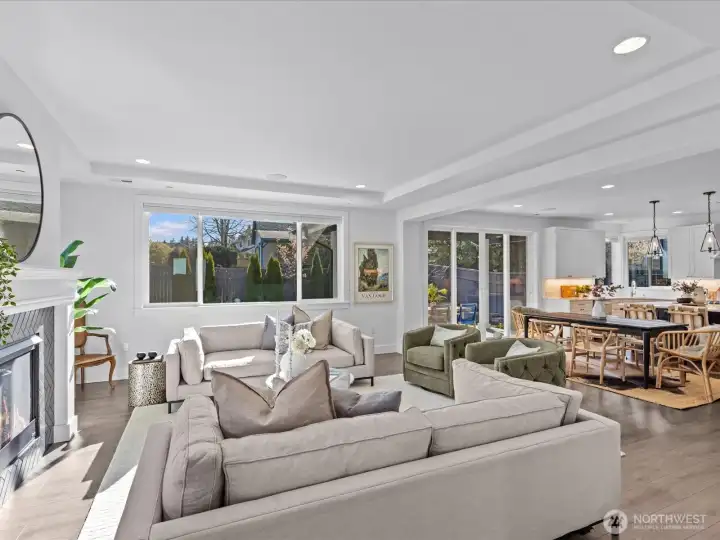 Sunlit great room with walls of windows that overlook the manicured rear yard