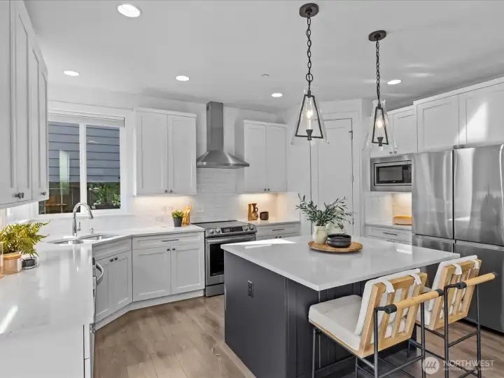 Beautifully appointed kitchen complete with quartz countertops, stainless appliance package, subway tile backsplash and step-in pantry