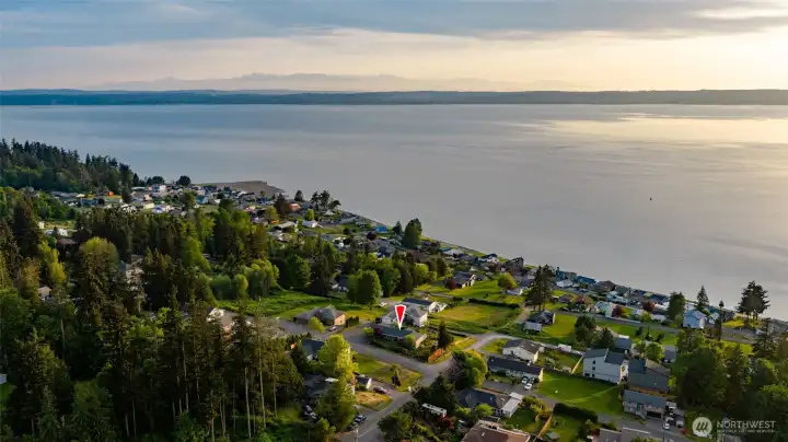 Red arrow indicates home, situated on a spacious corner lot, with unobstructed water views. The Olympic Mountains are in the background.