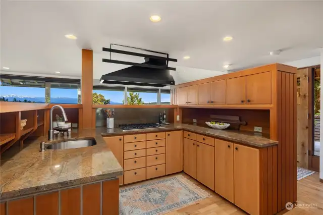 The kitchen features custom cabinetry topped with granite, Bosch dishwasher, Viking cooktop...