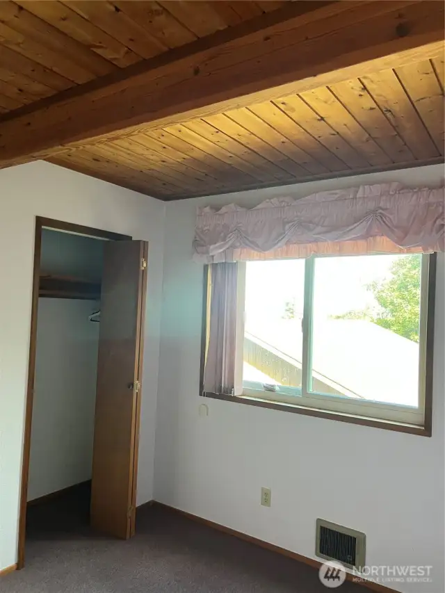 First guest bedroom with warm wood ceilings.