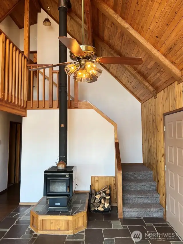 Slate floors surround the entrance, wood stove and leading to the upstairs loft and primary bedroom.