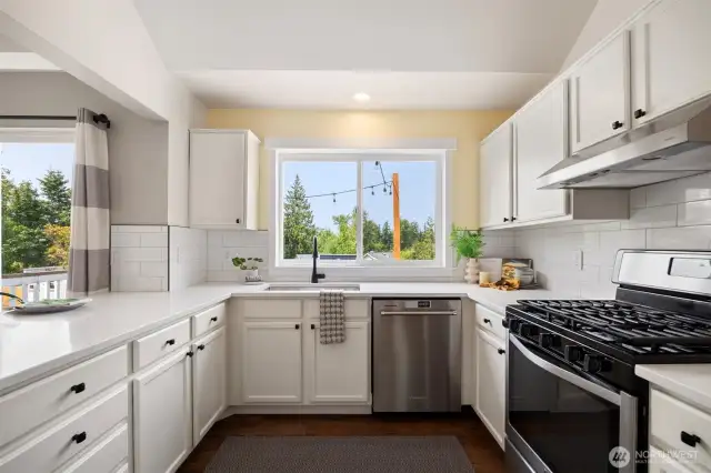 Overlooking the backyard, the kitchen features subway tile backsplash, quartz counters and stainless steel appliances.