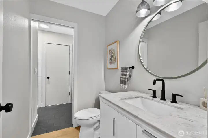 Guest bathroom on main level with separate shower and mudroom space, Door leads to exterior deck with hot tub.
