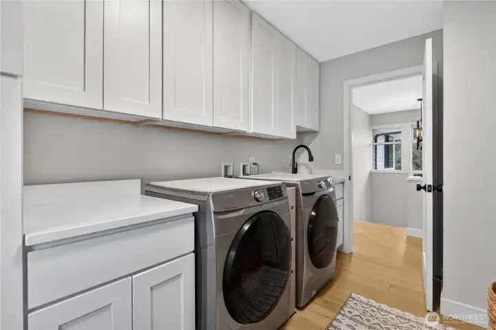 Large laundry space with lots of cabinets and utility sink