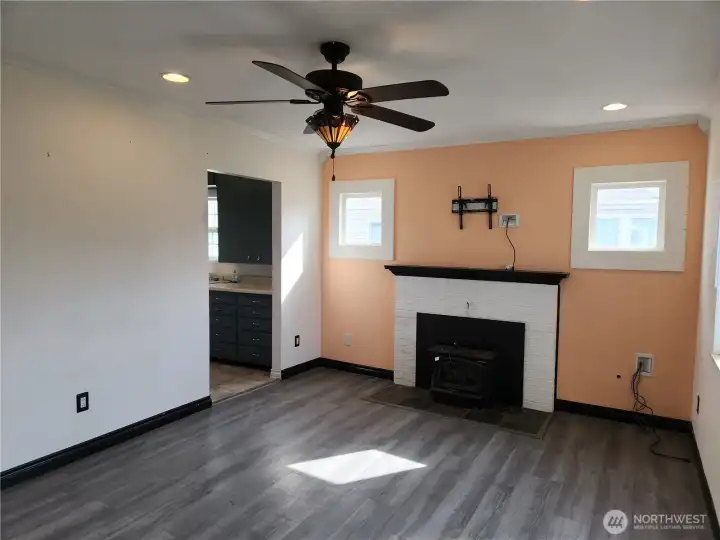 Another view of the living room with woodstove insert.  Open door way leads to kitchen.