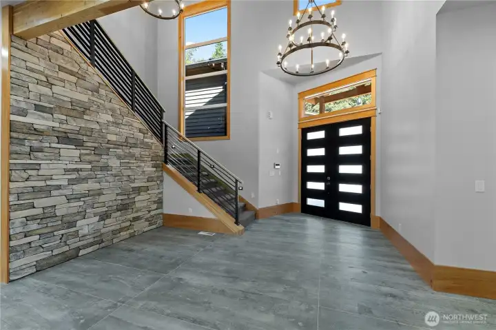 Grand entry with vaulted ceilings, tile floors & stone wall.