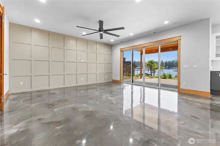 Lower living room with custom wood wall & fan with slider to backyard with water toy garage