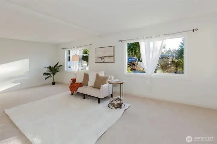 Bright and open living room with abundant natural light from multiple windows, offering a flexible layout for seating and everyday living.