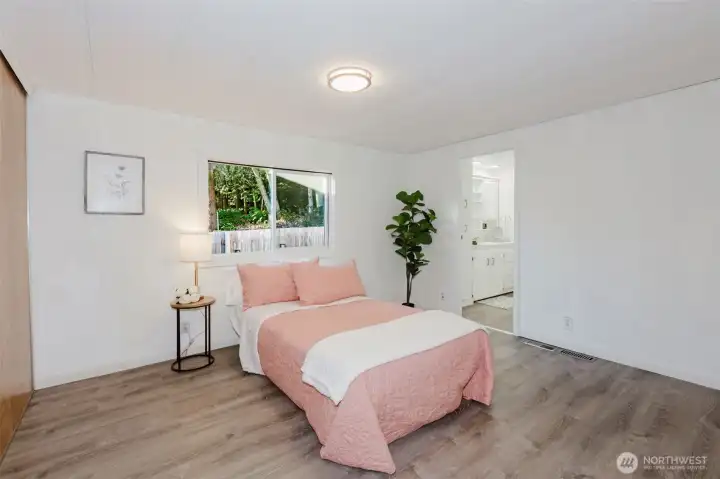 Spacious primary bedroom with updated flooring, natural light, and direct access to an ensuite bath.